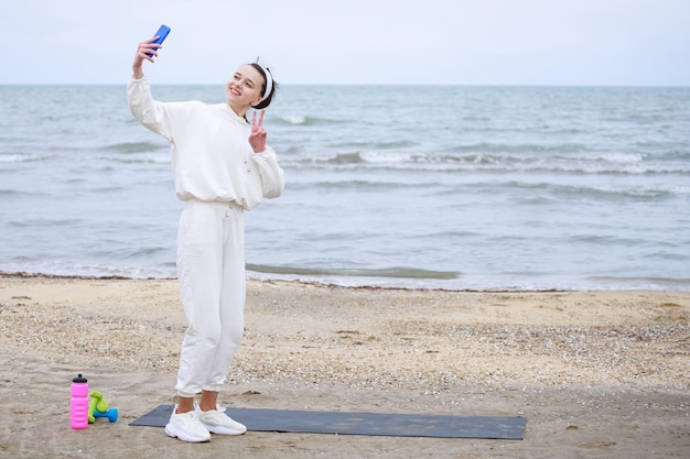 Спортсменка встает и делает селфи на пляже Фото высокого качества