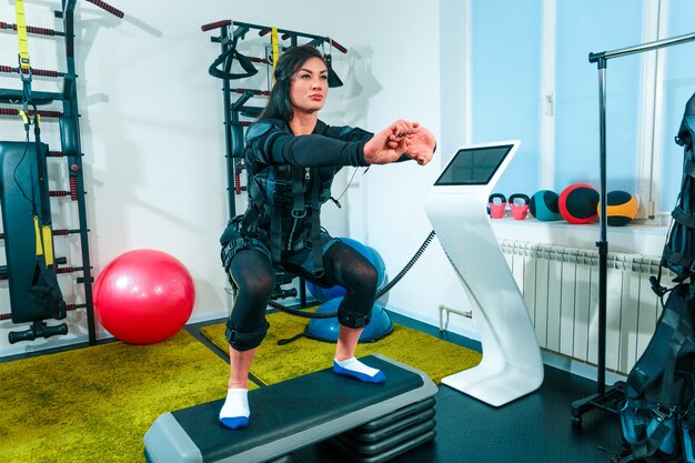 Спортсменка делает упражнения в фитнес-студии EMS