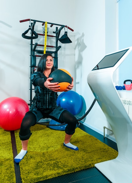 Спортсменка делает упражнения в фитнес-студии EMS