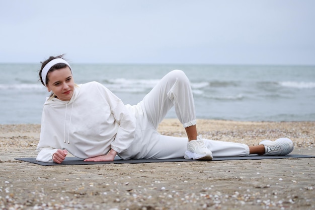 해변에서 요가 매트에 누워있는 여성 운동 선수 고품질 사진