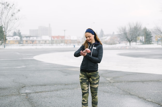 Free photo female athlete looking at time while exercising on street