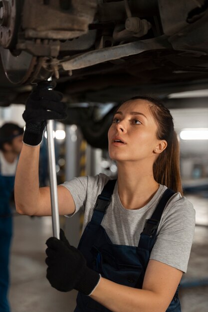 Foto gratuita riparatore automatico femminile che lavora nel negozio su un'automobile