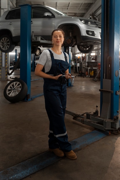 Foto gratuita riparatore automatico femminile che lavora nel negozio su un'automobile