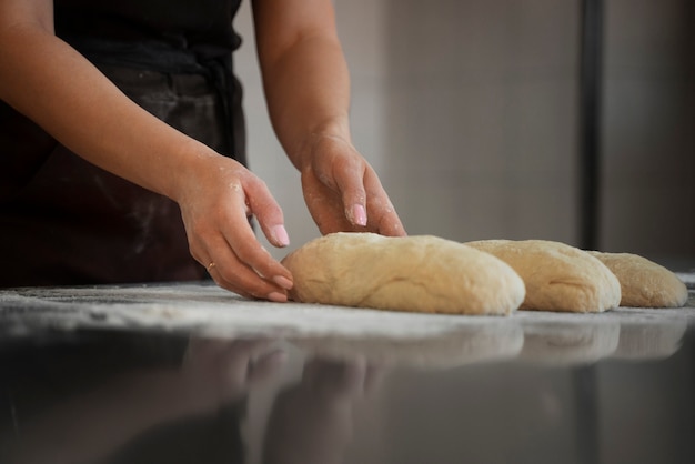 Foto gratuita panettiere femminile che maneggia la pasta di pane nella pasticceria