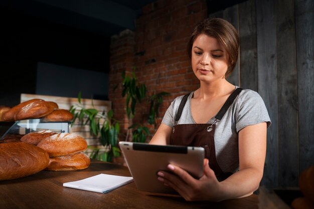태블릿으로 온라인 주문을 받는 가게의 여성 제빵사