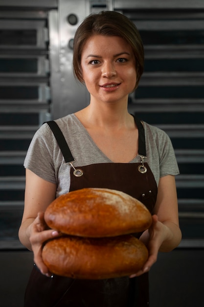 무료 사진 패스트리 가게에서 구운 빵을 들고 있는 여성 제빵사