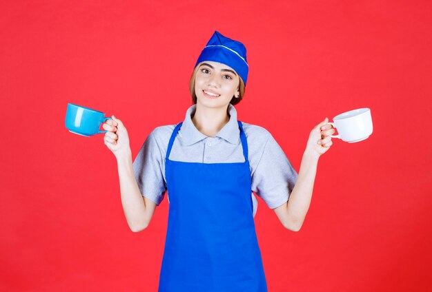 Female barista holding blue and white big cups