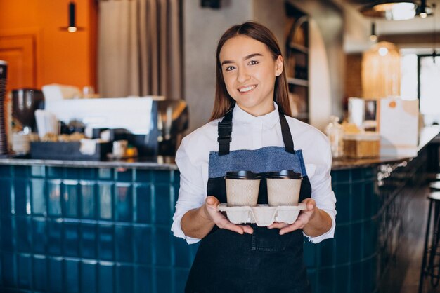 Female barista holding coffee prepared in cardboard cups