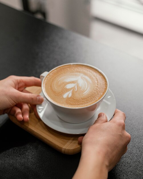 Женщина-бариста ставит украшенную чашку кофе на стойку