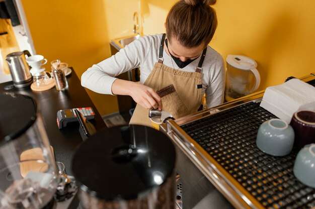 Female barista with mask working in the coffeehouse