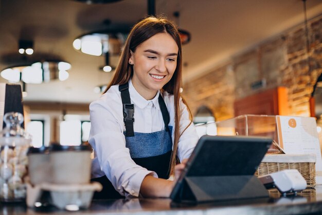 コーヒーショップで注文するタブレットを持つ女性のバリスタ