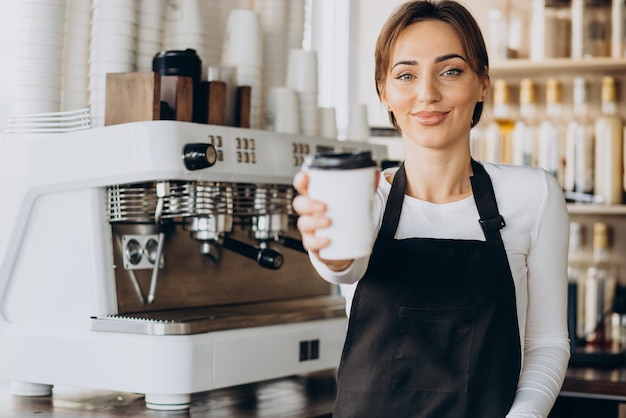 Lavoratrice barista in una caffetteria con in mano una tazza di caffè