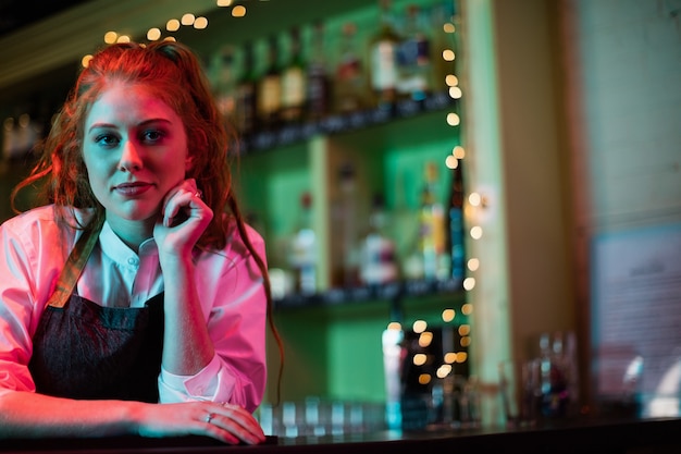 Женщина-бармен, опираясь на барную стойку