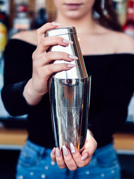 Female bartender preparing drink in shaker