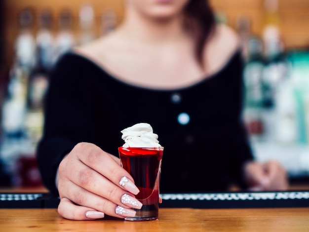 Женский бармен, обслуживающий красочный красный выстрел