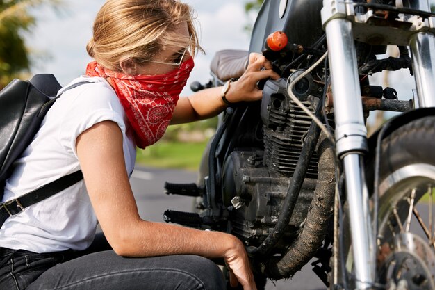 Женский байкер, ремонтирующий мотоцикл