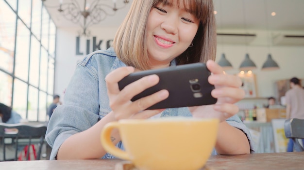 Female blogger photographing green tea cup in cafe with her phone. 