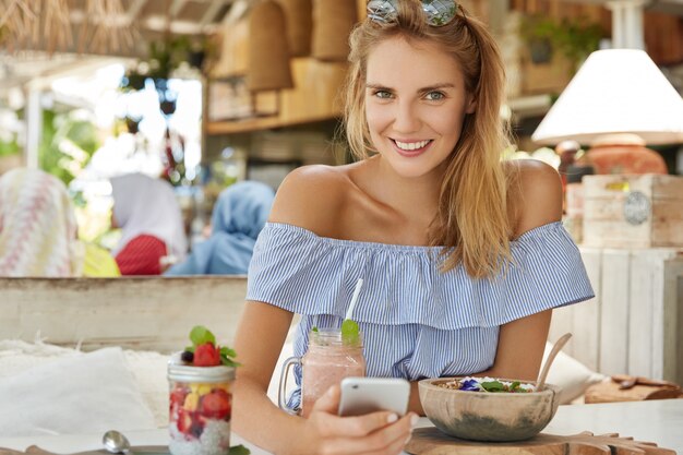 женщина-блогер отдыхает во время летних каникул в уютном ресторане, пишет фолловерам на личном сайте