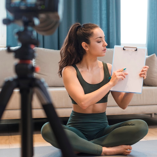 Female blogger in sportswear showing clipboard