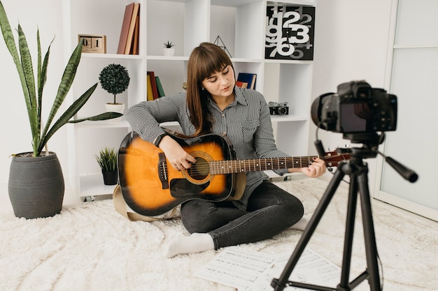 Женщина-блогер транслирует уроки игры на гитаре с камерой