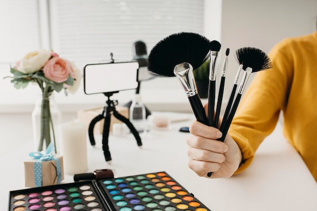 Foto gratuita blogger femminile in streaming set di pennelli per il trucco online con lo smartphone