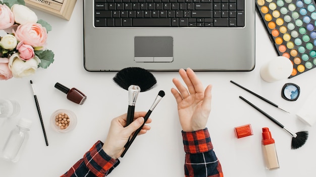 Female blogger streaming make-up products online with laptop