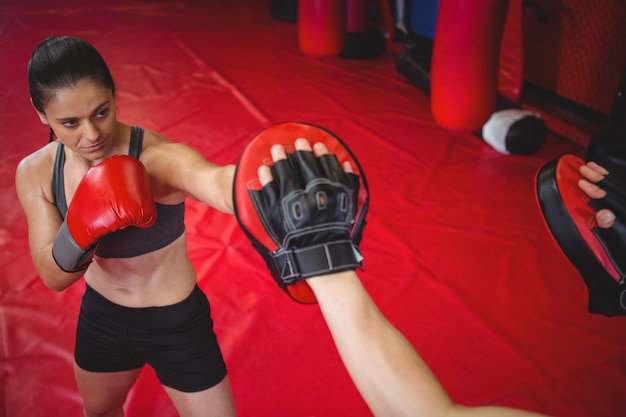 Female boxer practicing with trainer