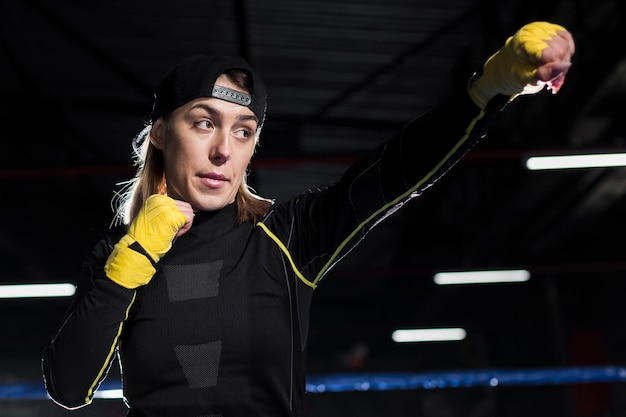 リングで練習する保護手袋の女性のボクサー