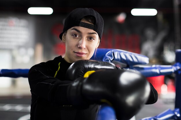 Female boxer smiling and posing in the ring with protective gloves