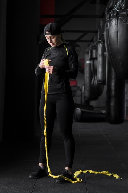 Female boxer trainer with elastic cord in the gym