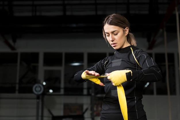 Free photo female boxer wrapping her hand in preparation for practice