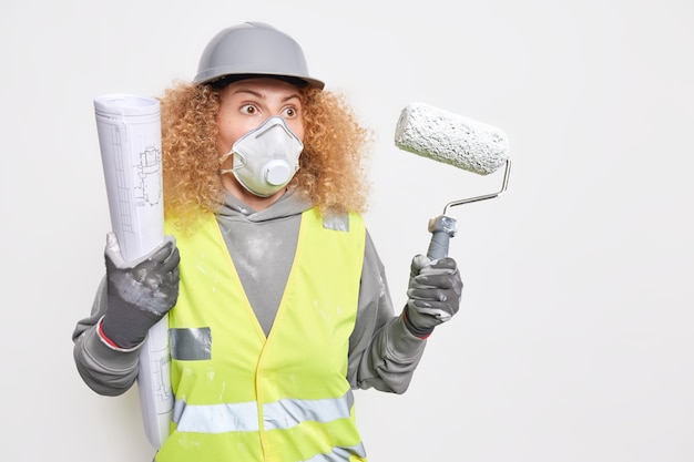 Female builder engineer holds architectural project and painting roller