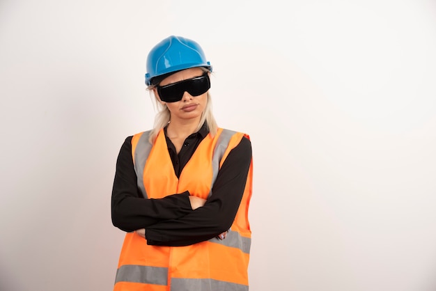 Женский строитель позирует с очками и шлемом. Фото высокого качества