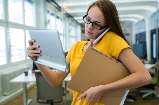 Female business executive holding a file and talking on mobile phone