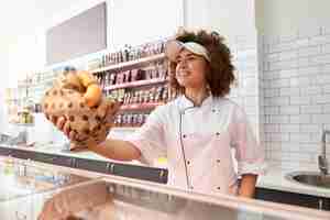 Free photo female butcher giving sausages from counter.