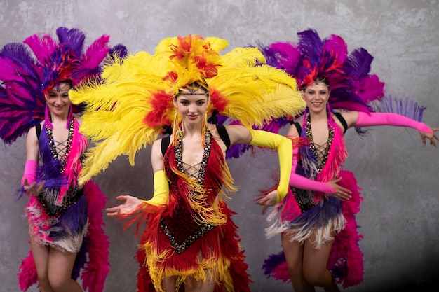 Female cabaret performers dancing backstage in feathers costumes