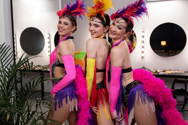 Female cabaret performers posing backstage in feathers costumes