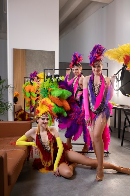 Female cabaret performers posing backstage in feathers costumes