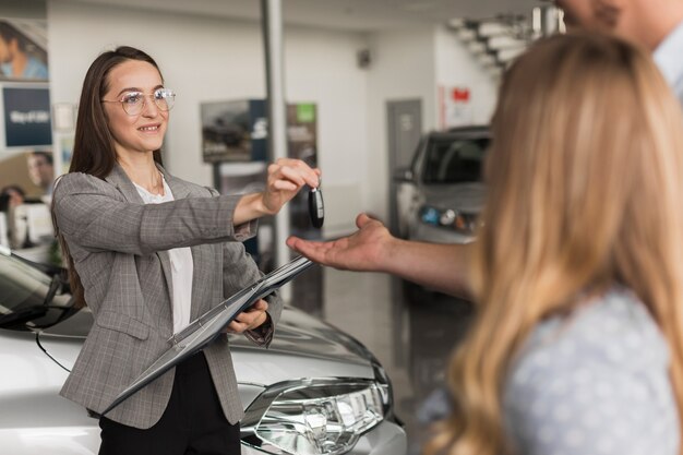 Female car dealer offering keys