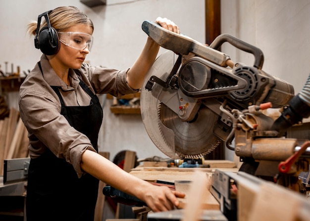 Female carpenter using electric saw in the studio