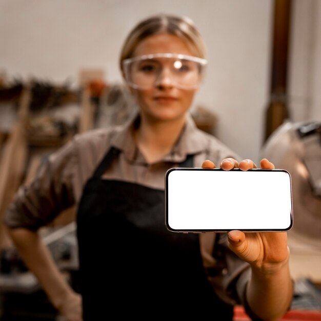 Female carpenter with glasses holding smartphone