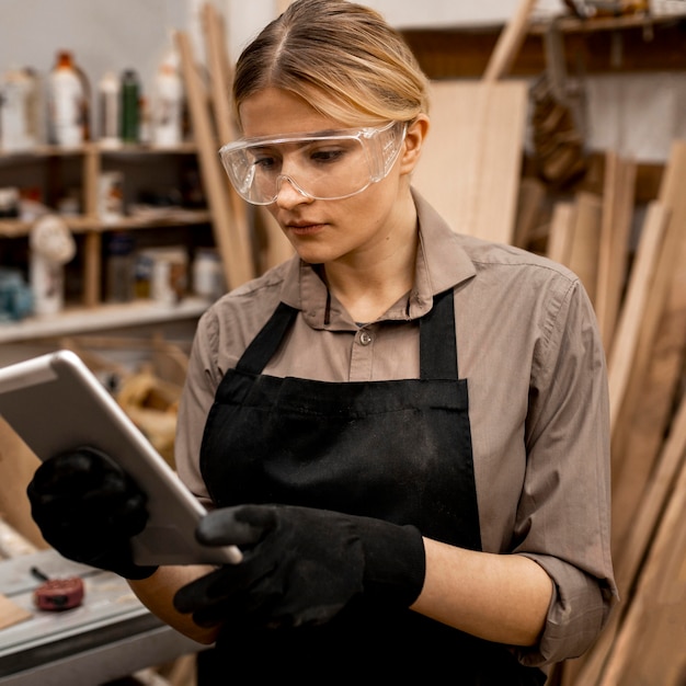 Female carpenter with safety glasses holding tablet