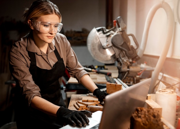 Female carpenter with safety glasses using laptop