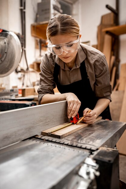 Female carpenter working in the studio with electric saw