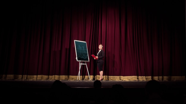 Женщина-спикер делает презентацию в зале на семинаре университета или бизнес-центра