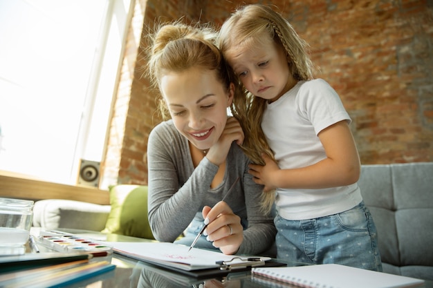 Female caucasian teacher and little girl, or mom and daughter. Homeschooling