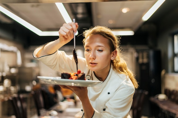 Free photo female chef carefully pouring sauce over dish