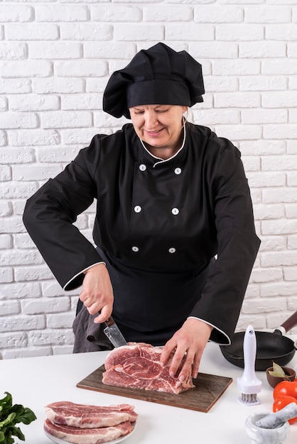 Female chef cutting meat