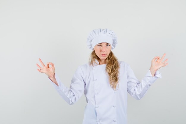 명상을 하 고 흰색 유니폼에 눈을 윙크하는 여성 요리사