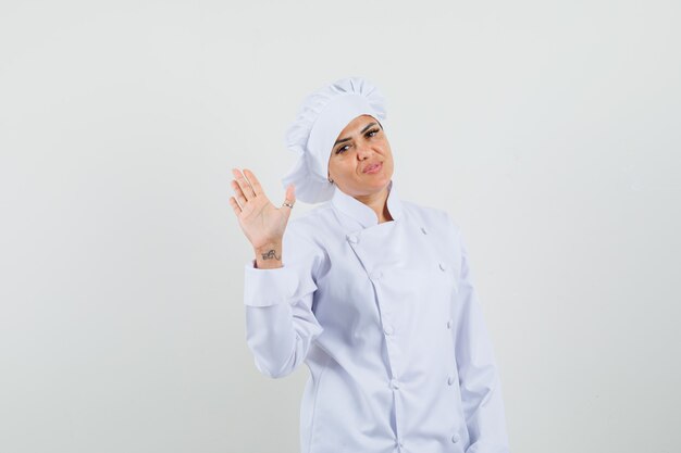 인사말 및 자신감을 찾고 흰색 유니폼 손을 흔들며 여성 요리사